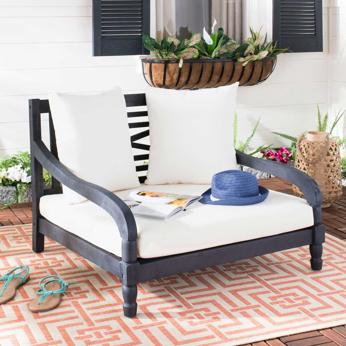 Dark slate gray wood arms curve around a generously cushioned beige outdoor lounger