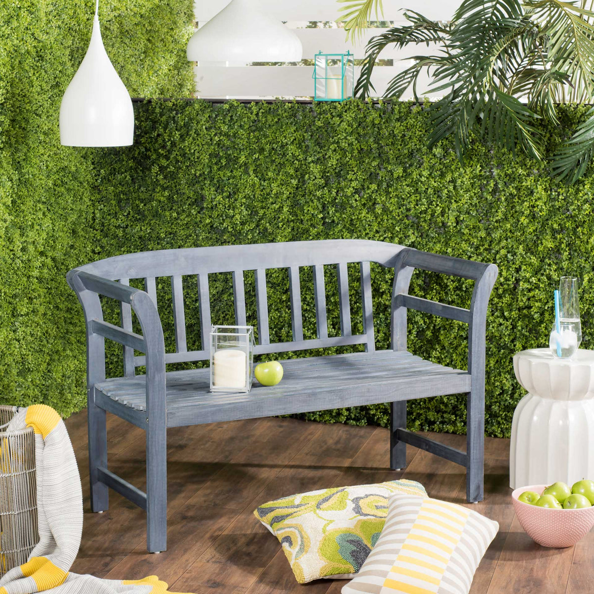 An ash gray slatted bench offers relaxed seating among lush patio greenery.