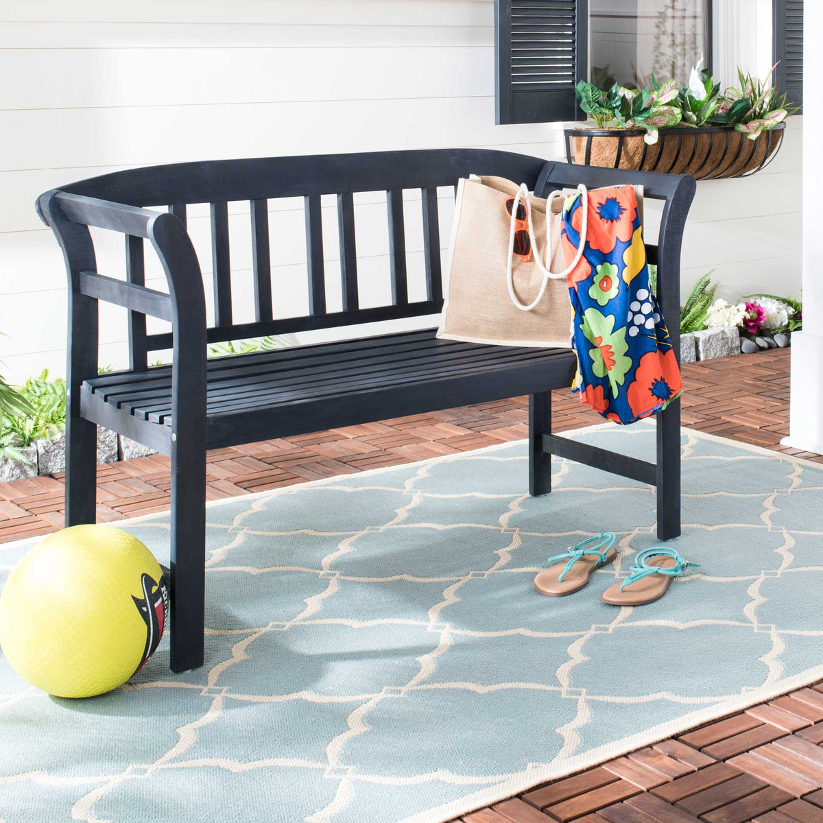 This dark slate gray bench pairs an open slatted seat with curved arms for inviting patio seating.