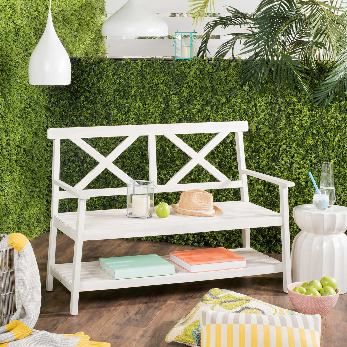 White outdoor bench brings classic X-back style and a handy lower shelf to a garden retreat.