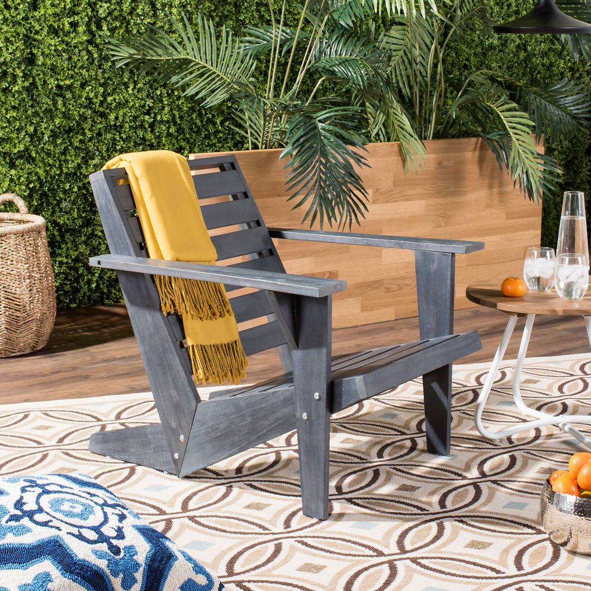 Dark gray wood Adirondack chair with a yellow throw for relaxed outdoor lounging