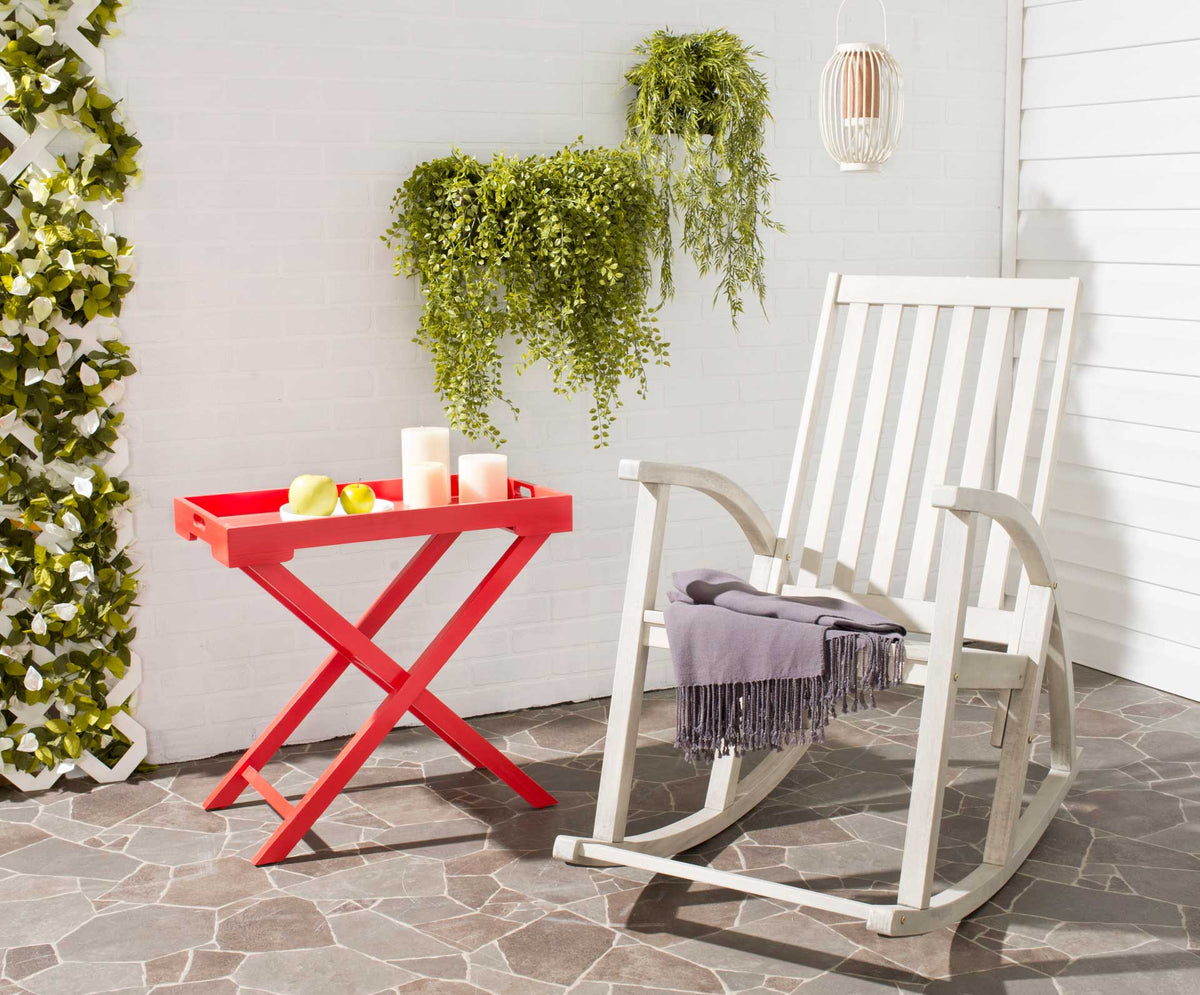 Whitewashed acacia rocker with a tall slatted back and a soft gray throw on a stone patio