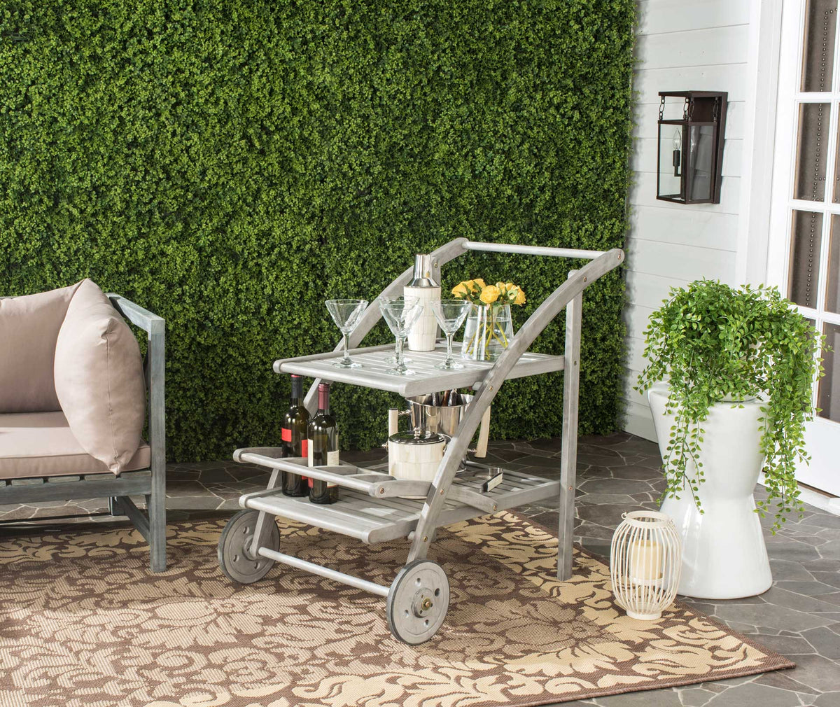 A gray-washed wood cart keeps drinks, glassware, and flowers within reach on the patio.