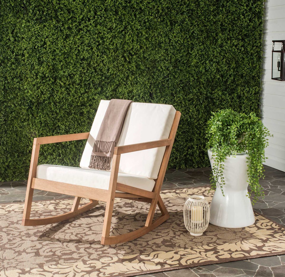 A natural wood rocker with pale cushions brings relaxed comfort to a leafy patio nook.
