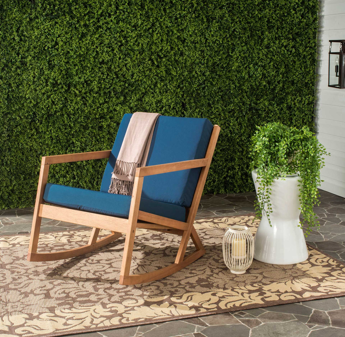 Navy cushions give a natural wood rocker a bold accent amid leafy patio greenery.