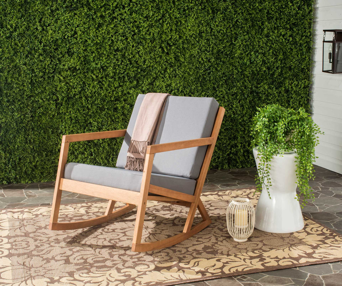 Charcoal cushions and warm wood tones create a welcoming seat on a leafy patio.