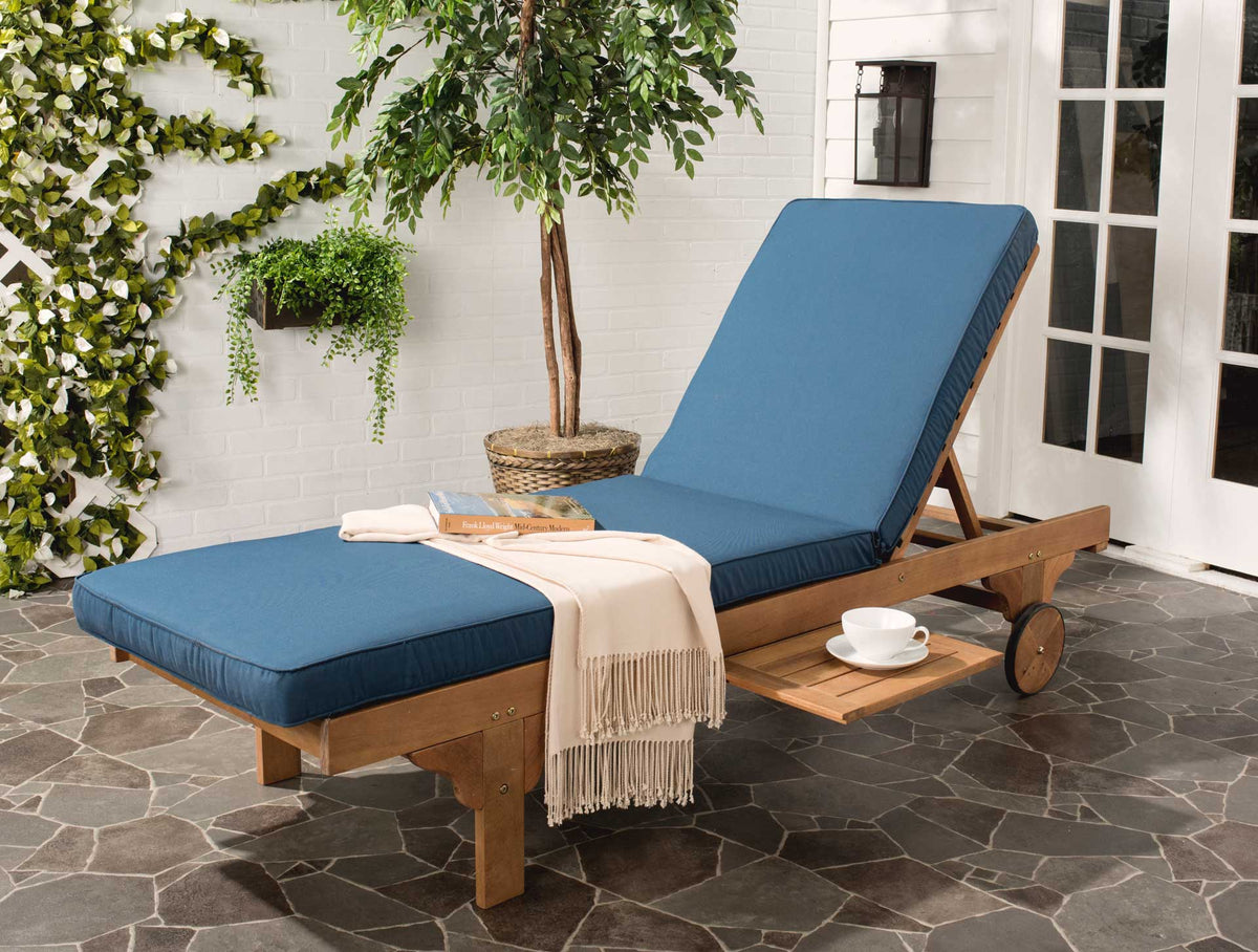A navy-cushioned chaise lounge with a raised backrest and slide-out tray rests on a wheeled wood frame.