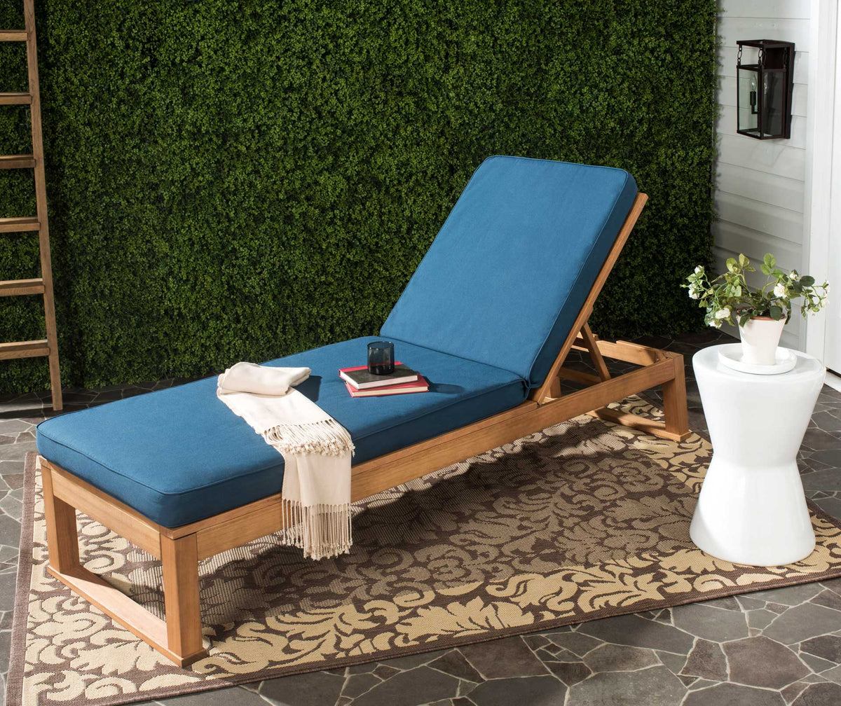 A navy cushion adds rich color to the warm wood lounger on a garden patio.