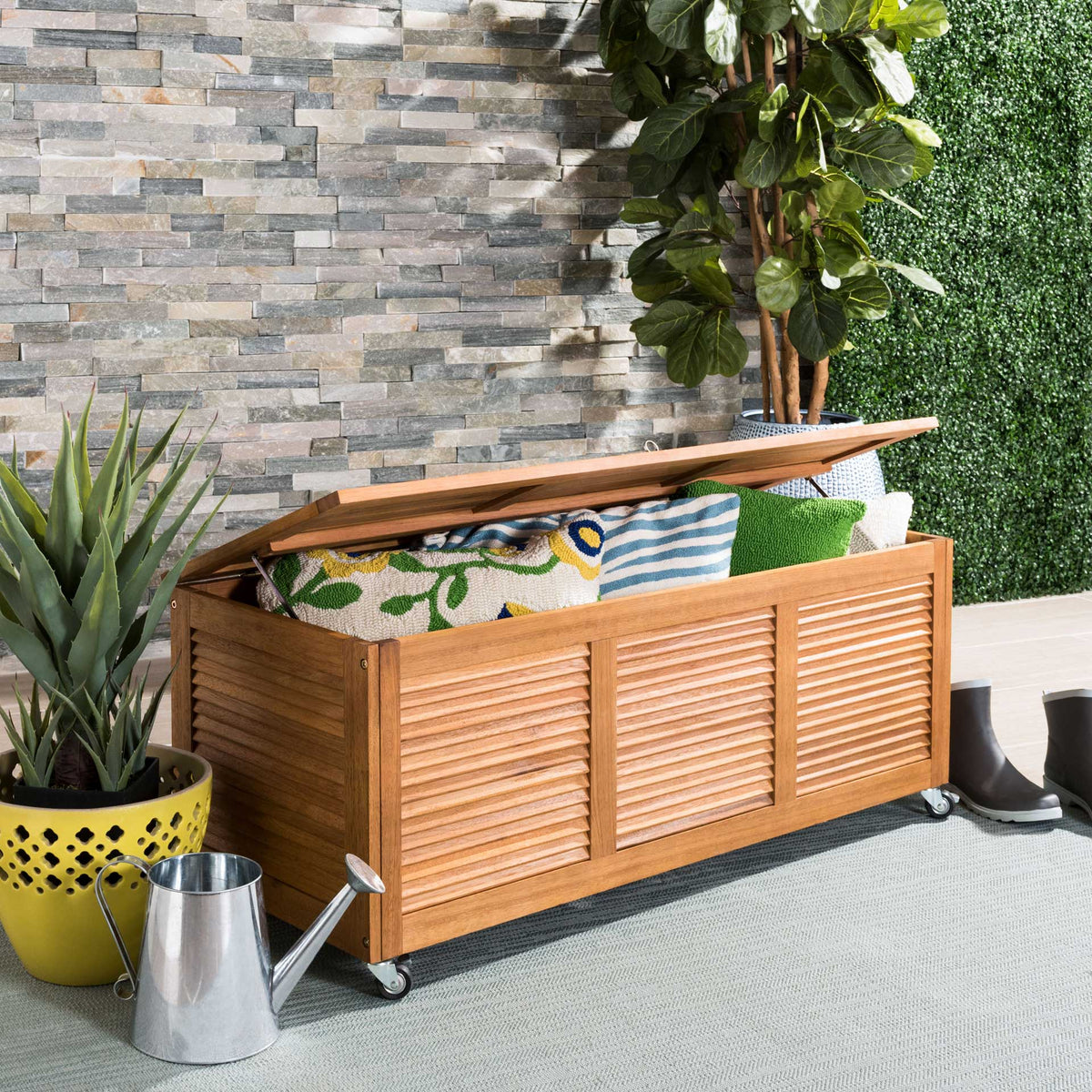 Natural wood cushion box holds outdoor pillows beneath its easy-lift slatted lid