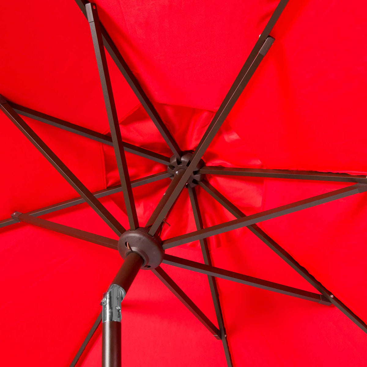 Dark ribs converge beneath the red canopy beside a metal tilt joint