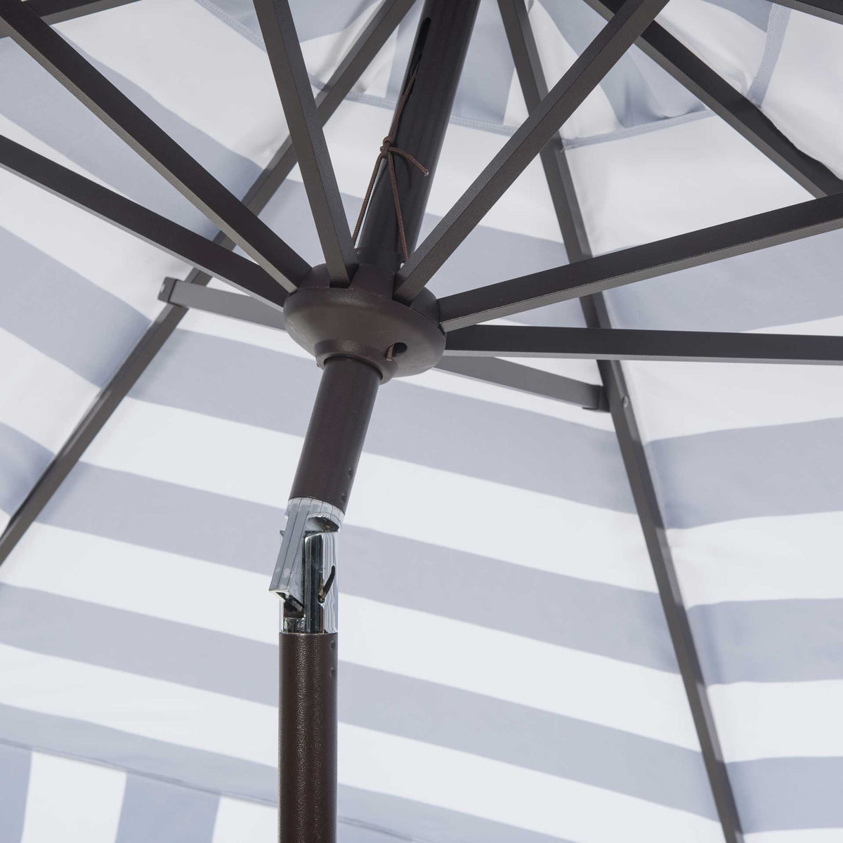 An eight-rib metal frame meets above the hinged tilt joint beneath a striped canopy.