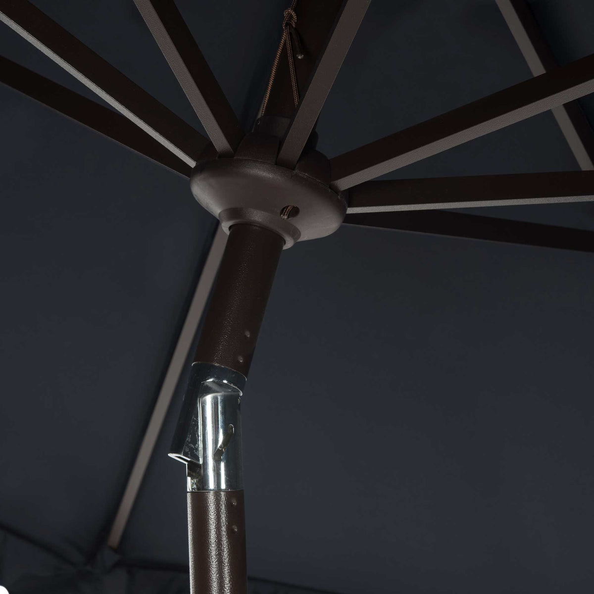 Eight metal ribs converge beneath navy fabric around a central hub and silver tilt hinge.
