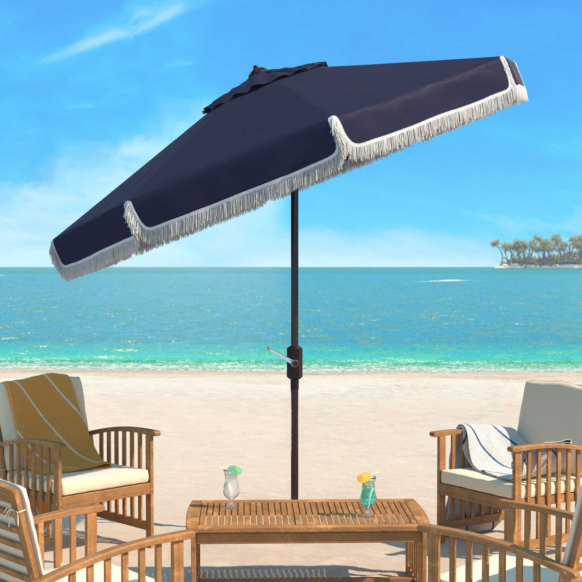 A navy umbrella tilts above a coastal patio table, finished with white fringe.