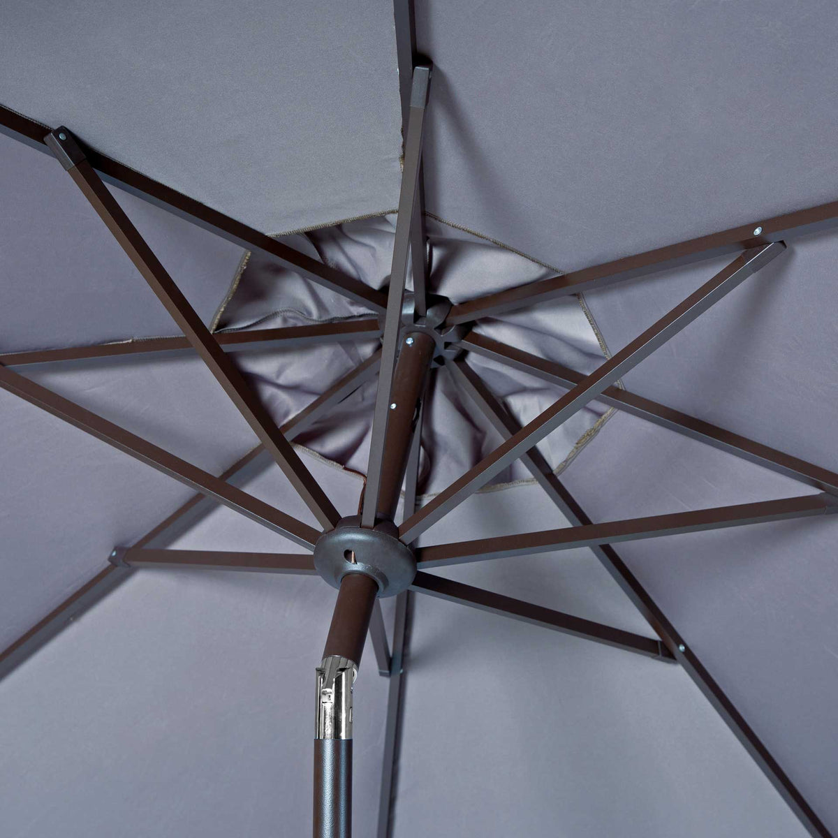 Brown metal ribs converge beneath the gray canopy around a central hub and tilt joint.