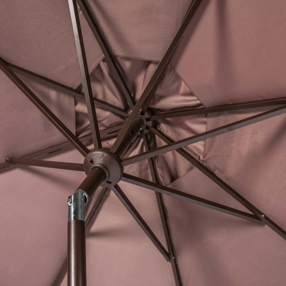 Brown metal ribs meet at a sturdy hub beneath the taupe fabric canopy