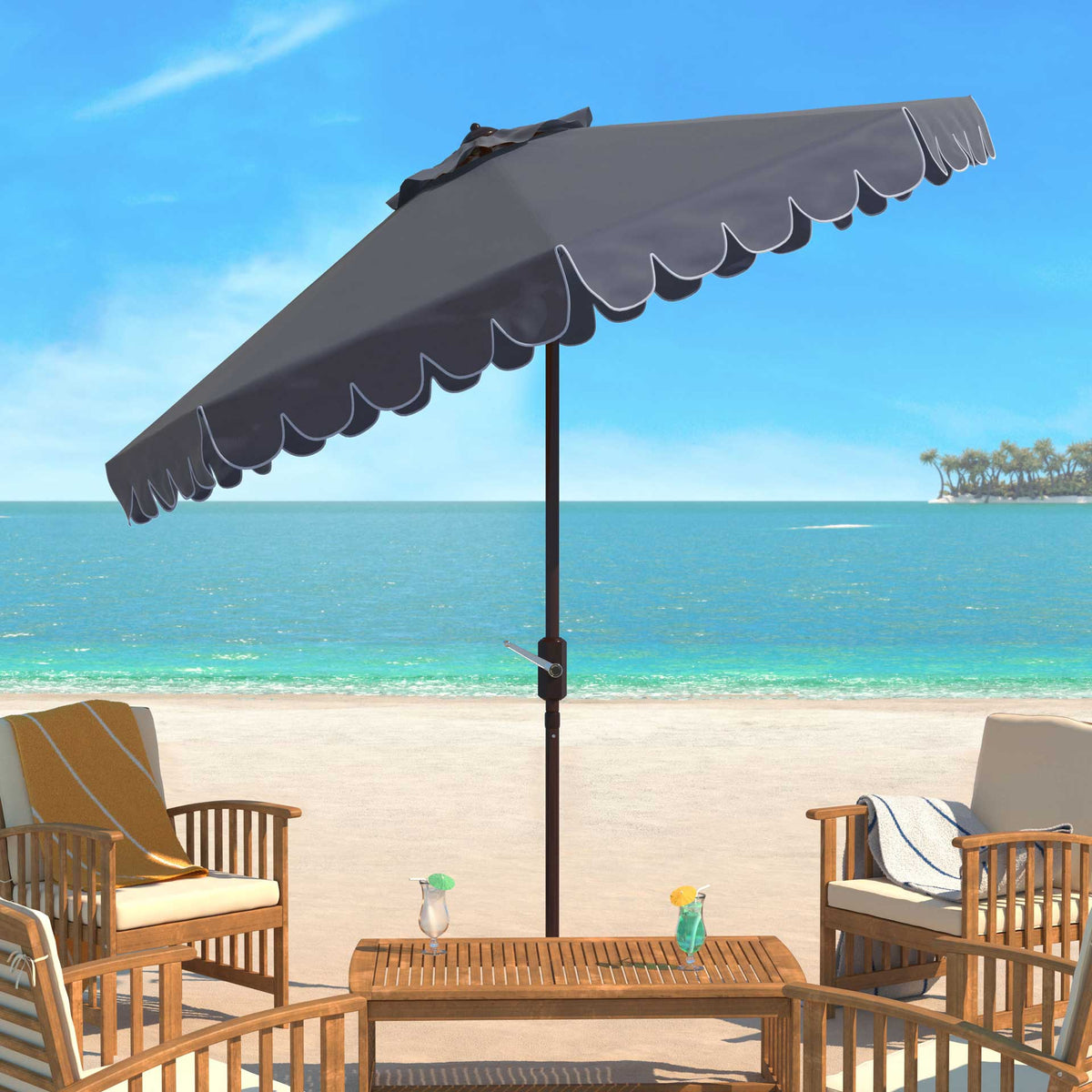 Taupe umbrella with white-edged scallops shades a seaside patio seating area