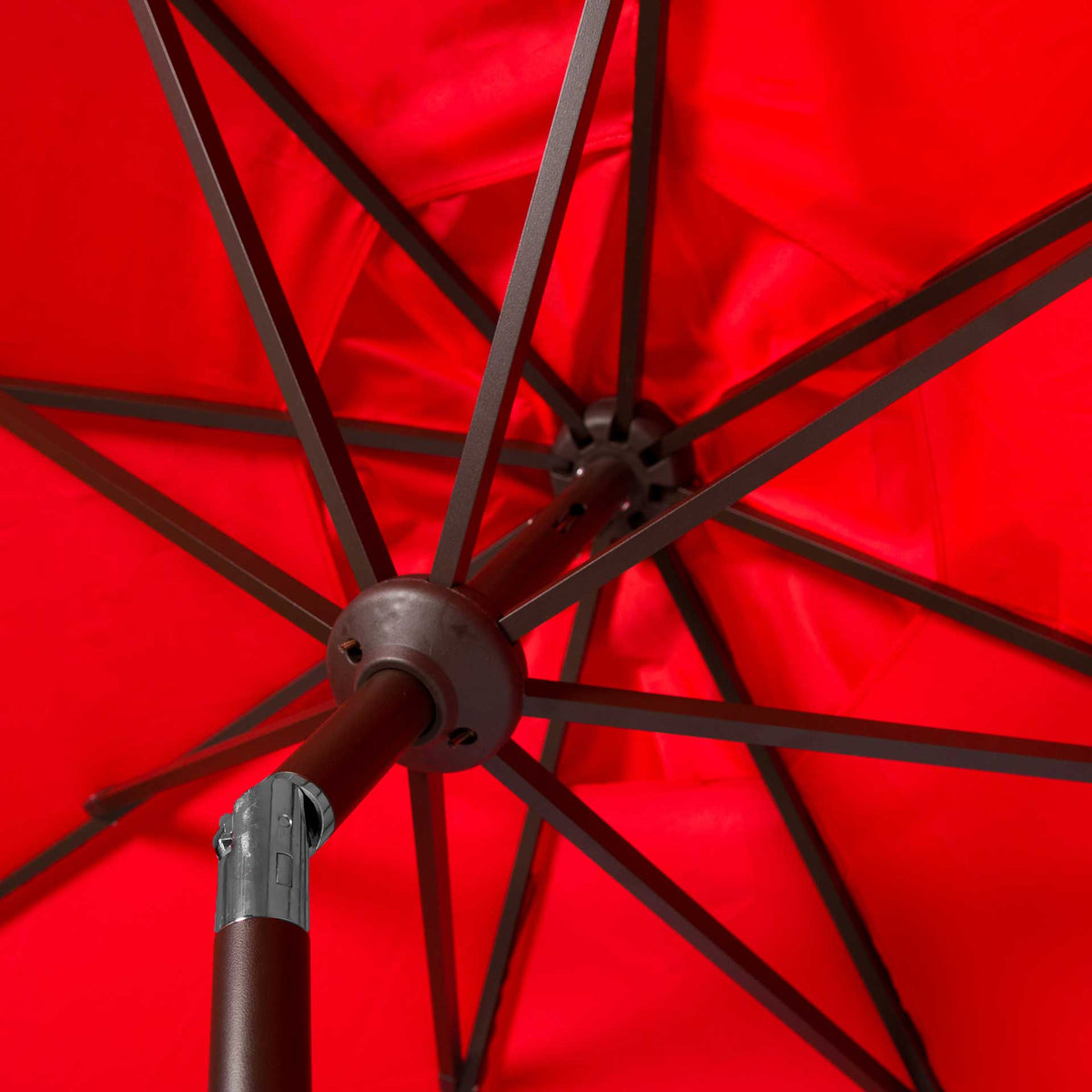 Brown metal ribs meet at a central hub under the vivid red fabric canopy