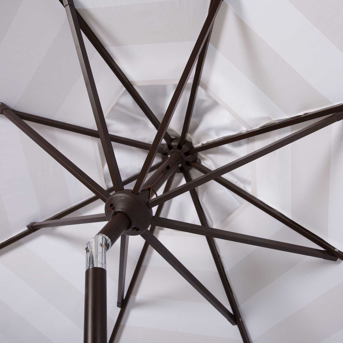 Brown metal ribs and a silver tilt joint support the beige and white canopy