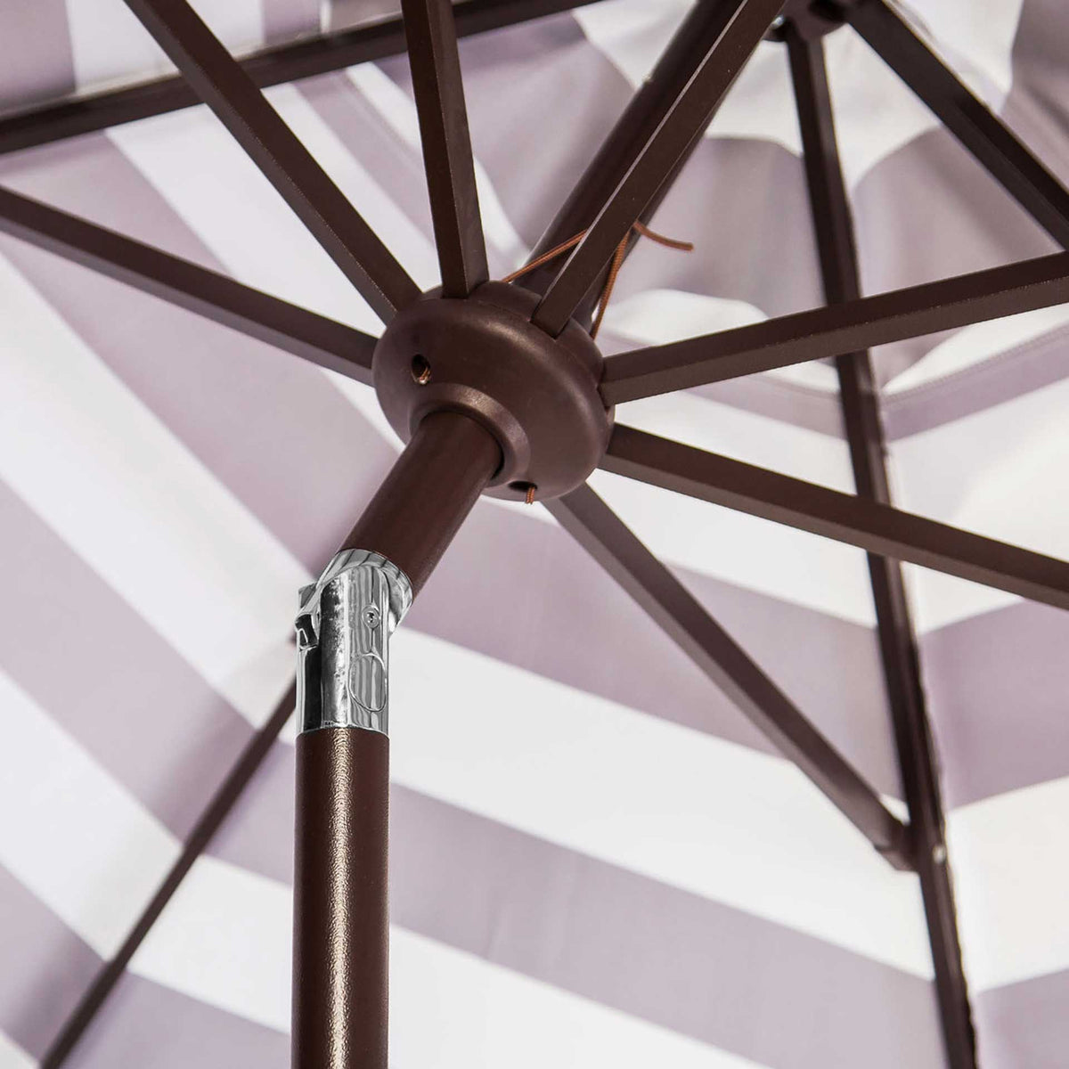 Brown metal ribs meet beneath the black and white canopy beside a silver tilt joint