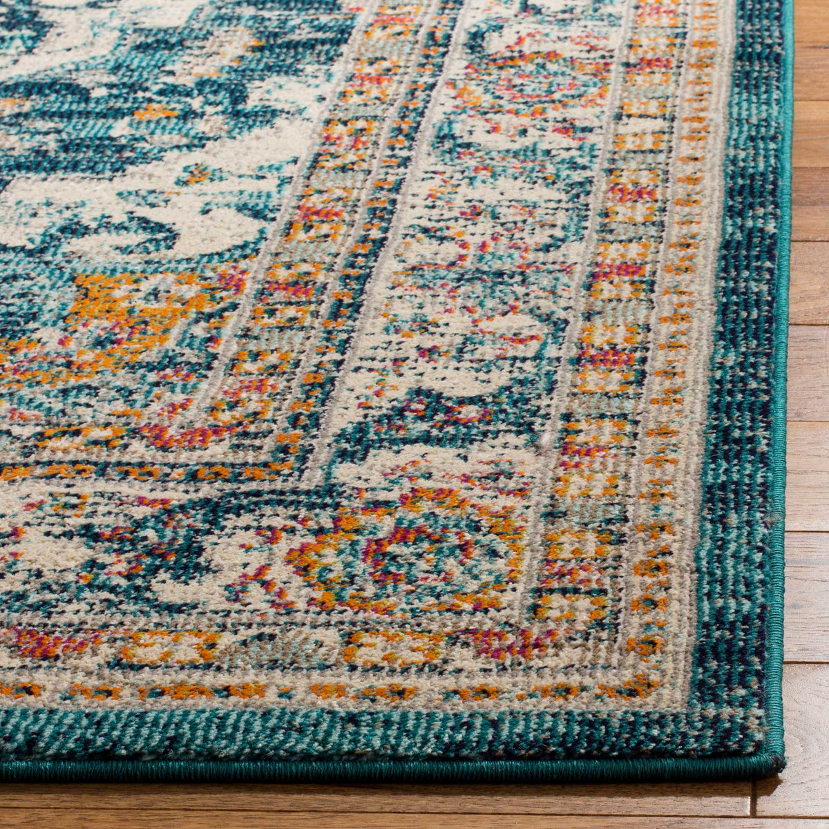 A teal-bound edge frames intricate ivory, blue, and orange motifs on the rug