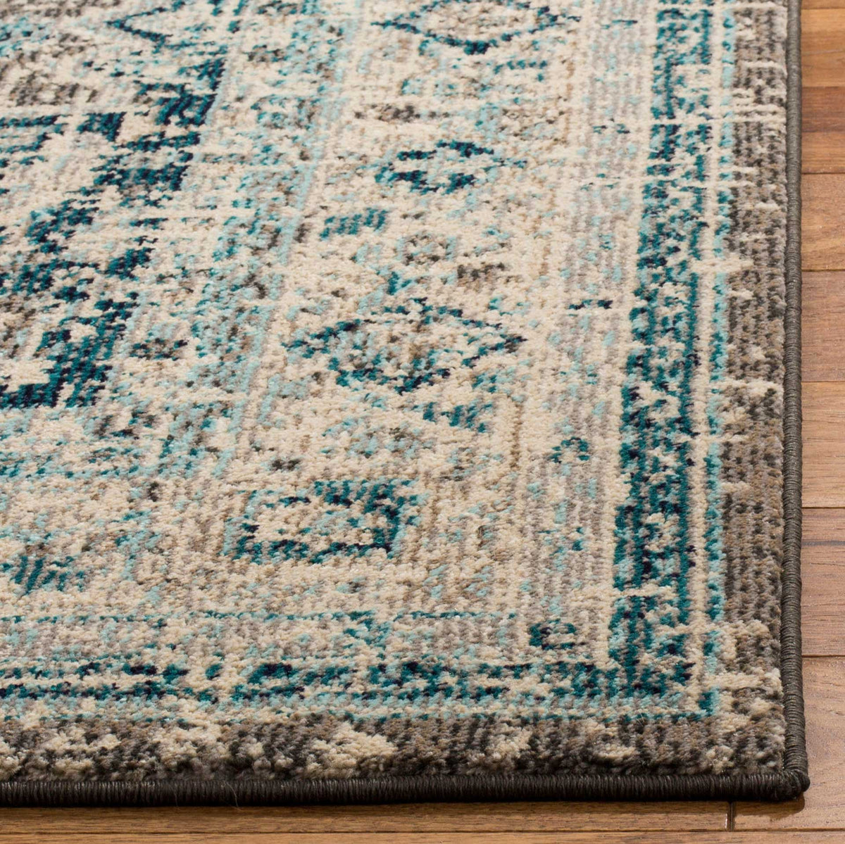 A neatly bound edge frames the rug's textured ivory, blue, and gray floral motifs.