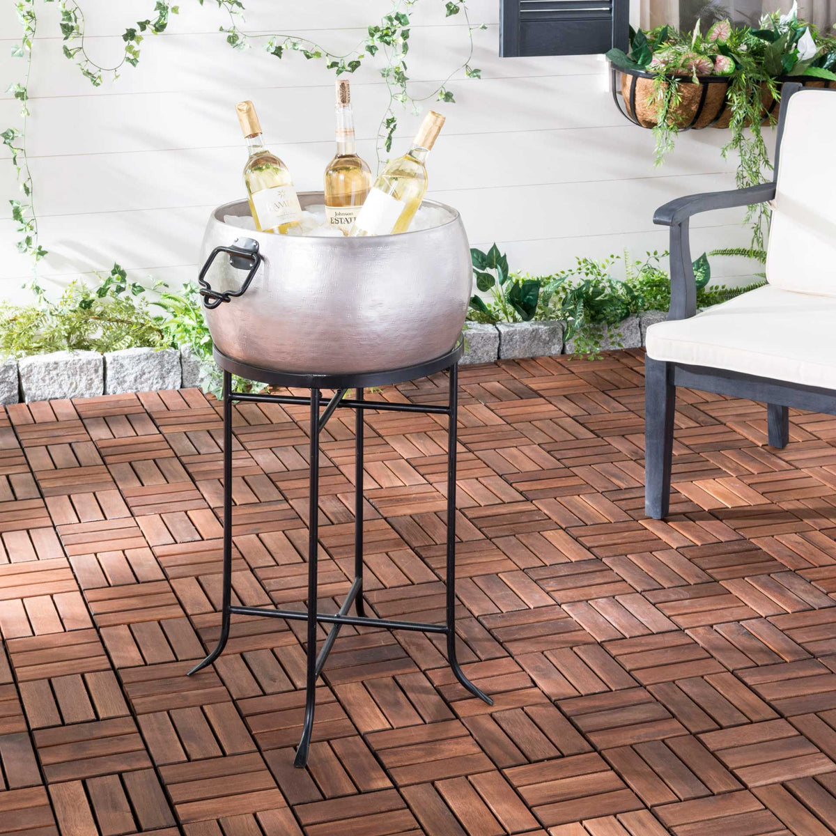 Pewter beverage tub on a tall black stand keeps chilled bottles within easy reach outdoors.