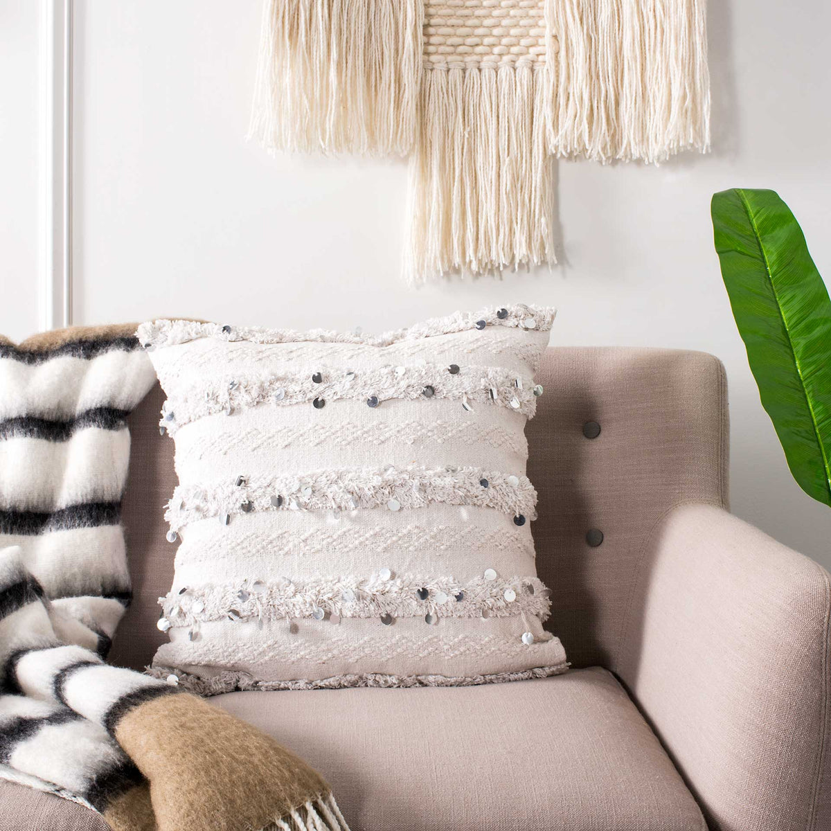Fringed white pillow with shimmering accents adds an inviting touch to a cozy armchair