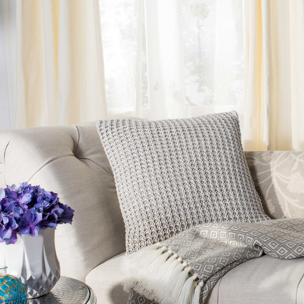 A chunky gray knit pillow layers inviting texture on a neutral sofa
