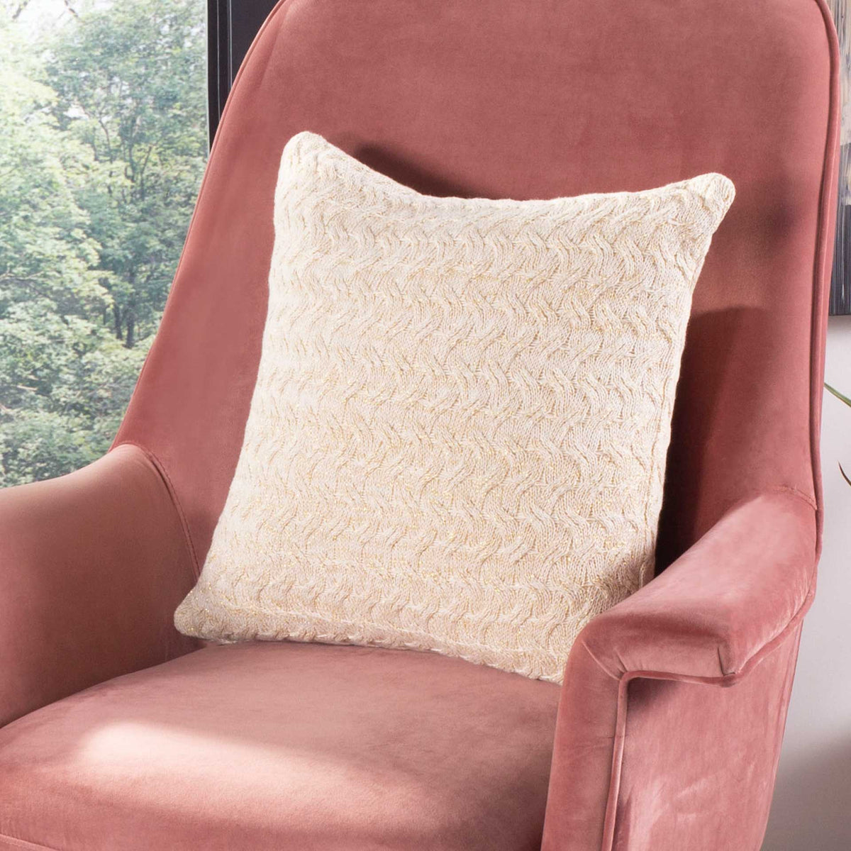 Natural and gold knit pillow adds cozy texture to a pink upholstered chair