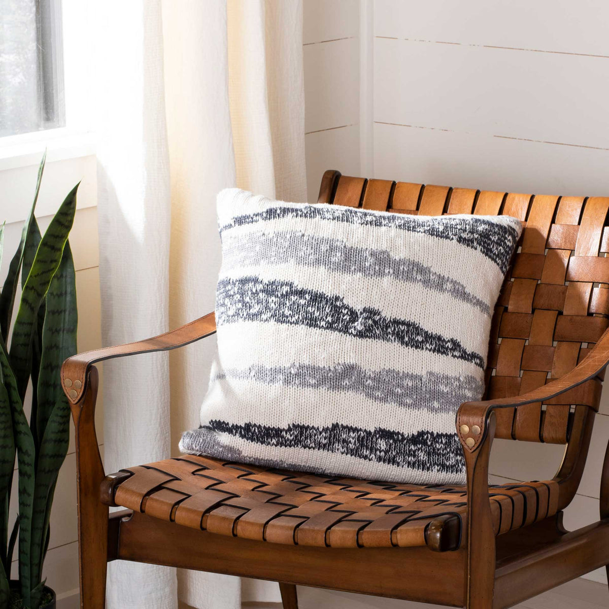Plump square pillow with layered gray knit stripes and a cozy, relaxed texture