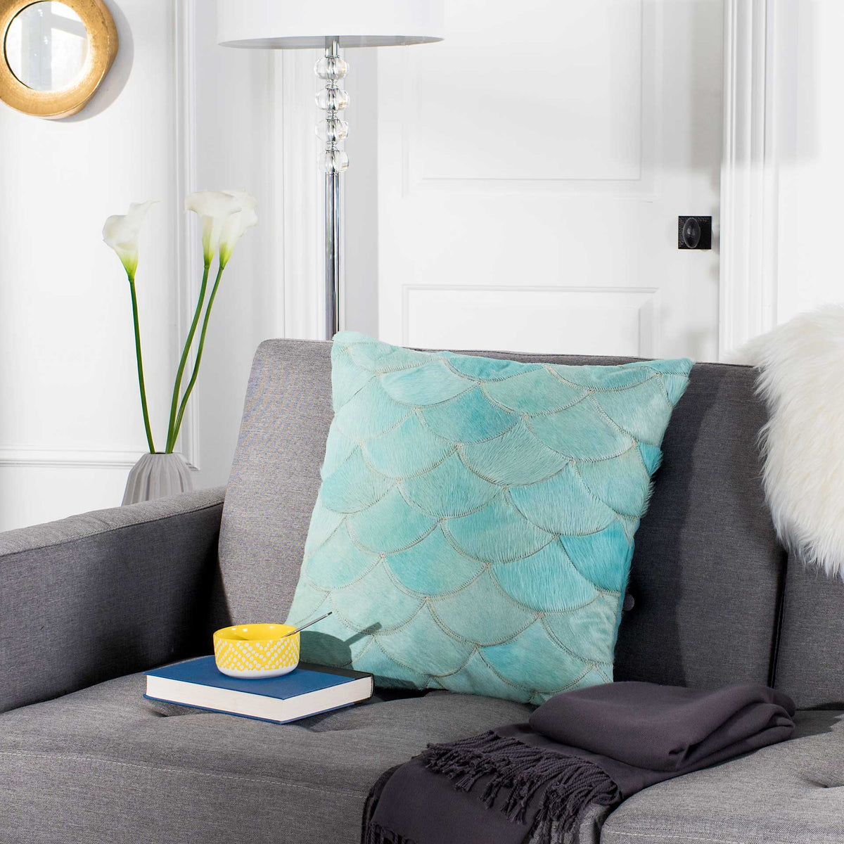 Teal scalloped cowhide pillow adds soft texture and color to a gray sofa