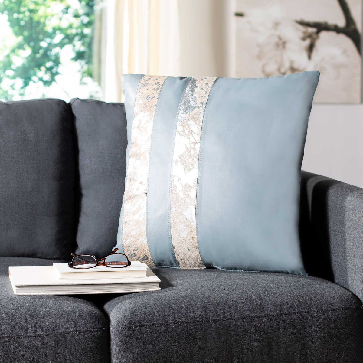 Gray pillow with vertical cowhide bands brings soft metallic shimmer to a charcoal sofa