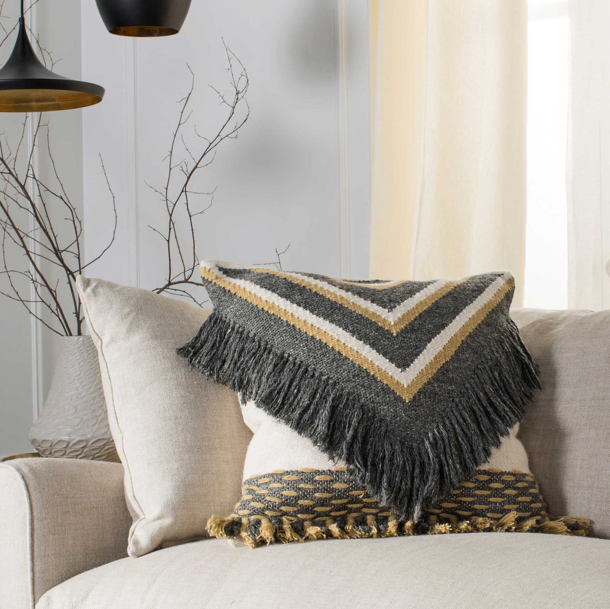 Chevron stripes and cascading charcoal fringe lend bold texture to a neutral sofa