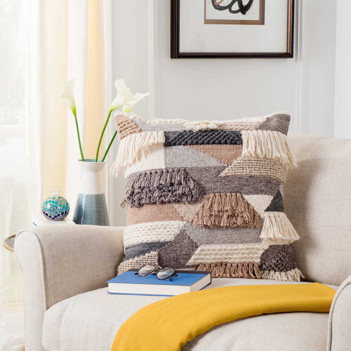 Layered neutral weaves and playful fringe bring cozy texture to a square accent pillow