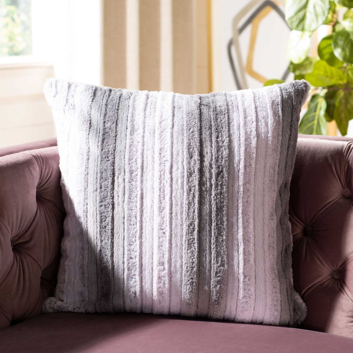 A textured gray and white pillow brings cozy contrast to a tufted sofa