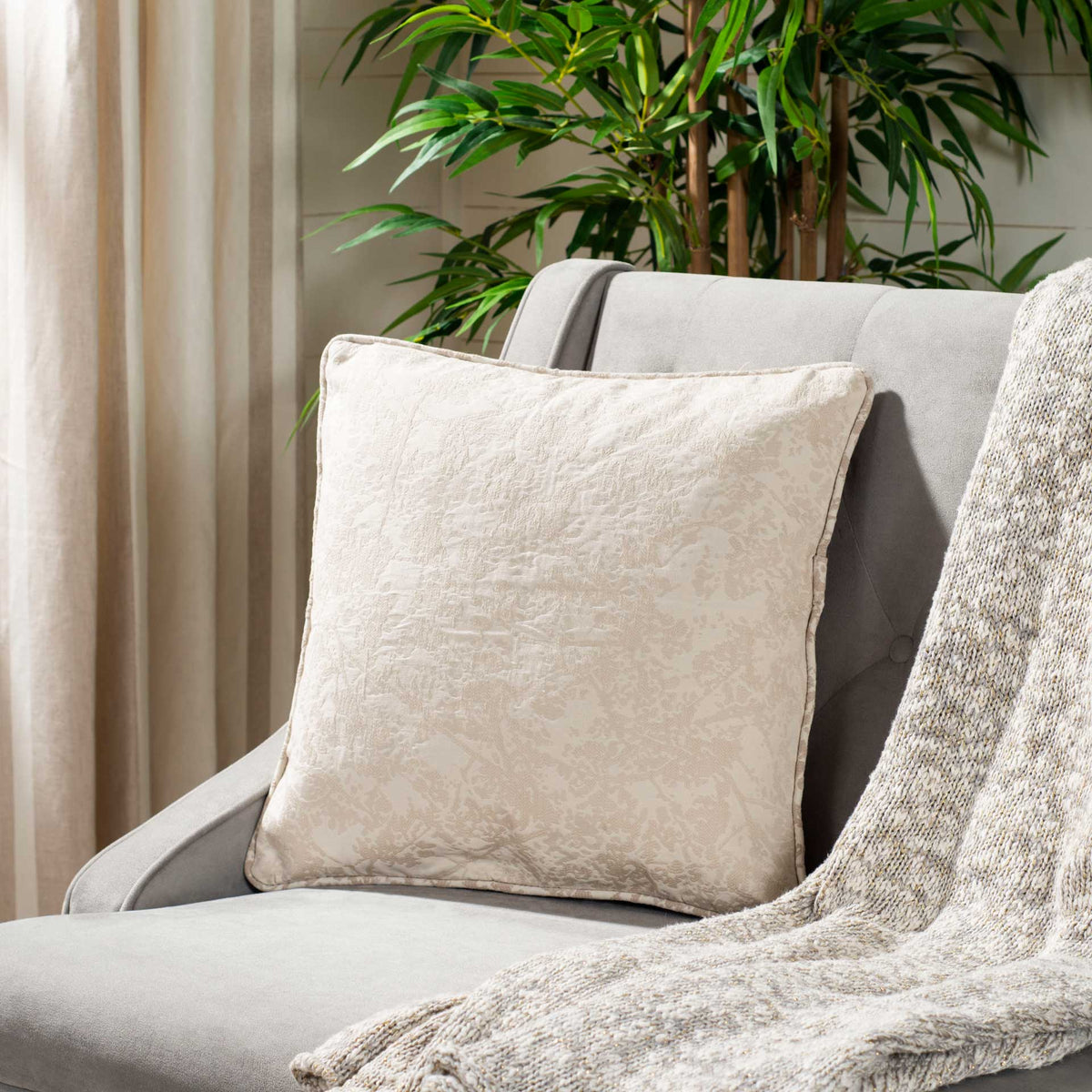 Plush neutral accent pillow with a subtle floral pattern and soft texture
