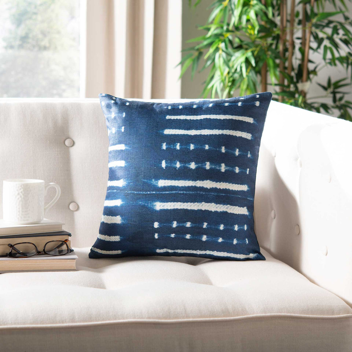 Deep blue square pillow with horizontal white stripes and dots lends graphic style to a light sofa