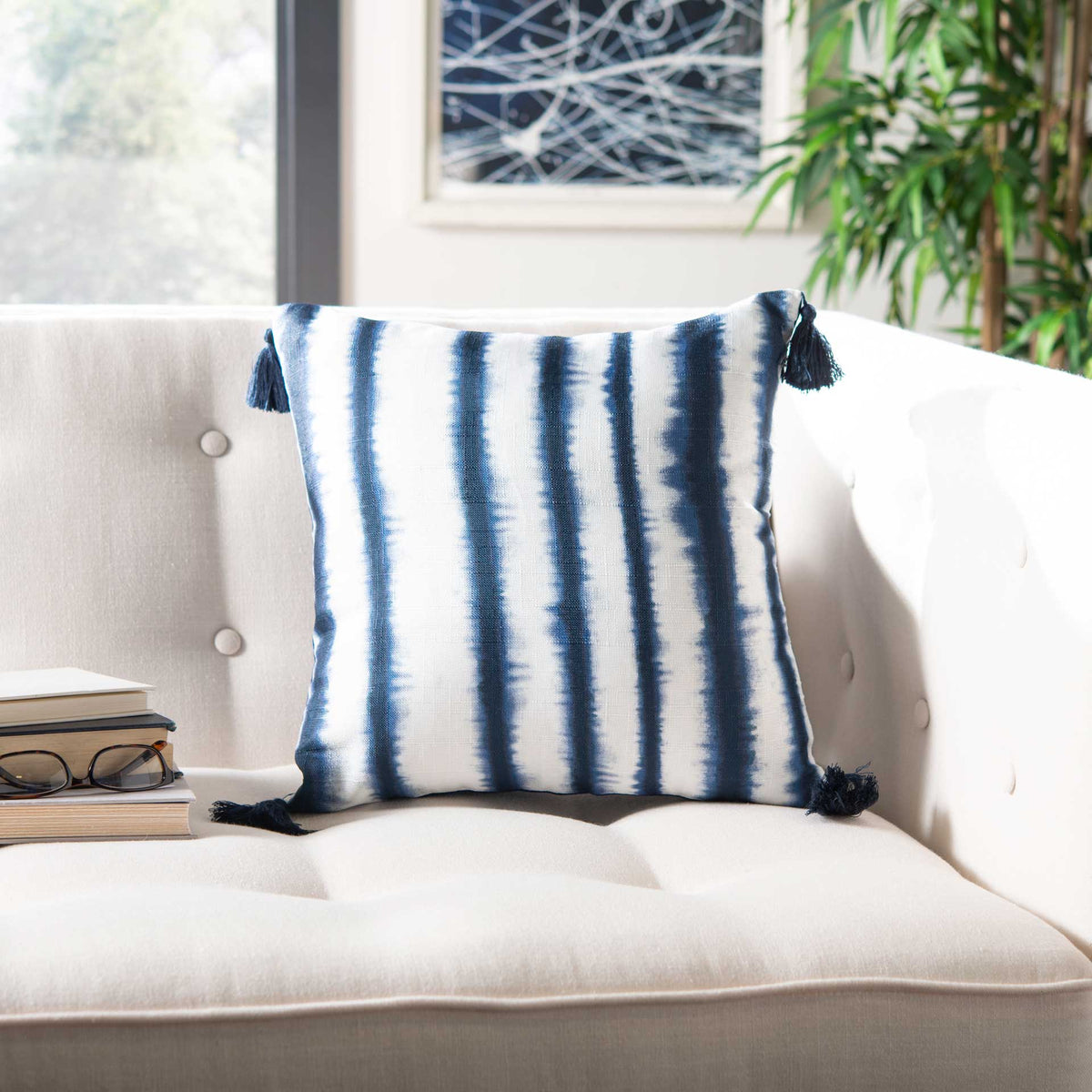 Navy stripes and corner tassels add casual color to this soft pillow on a white sofa.