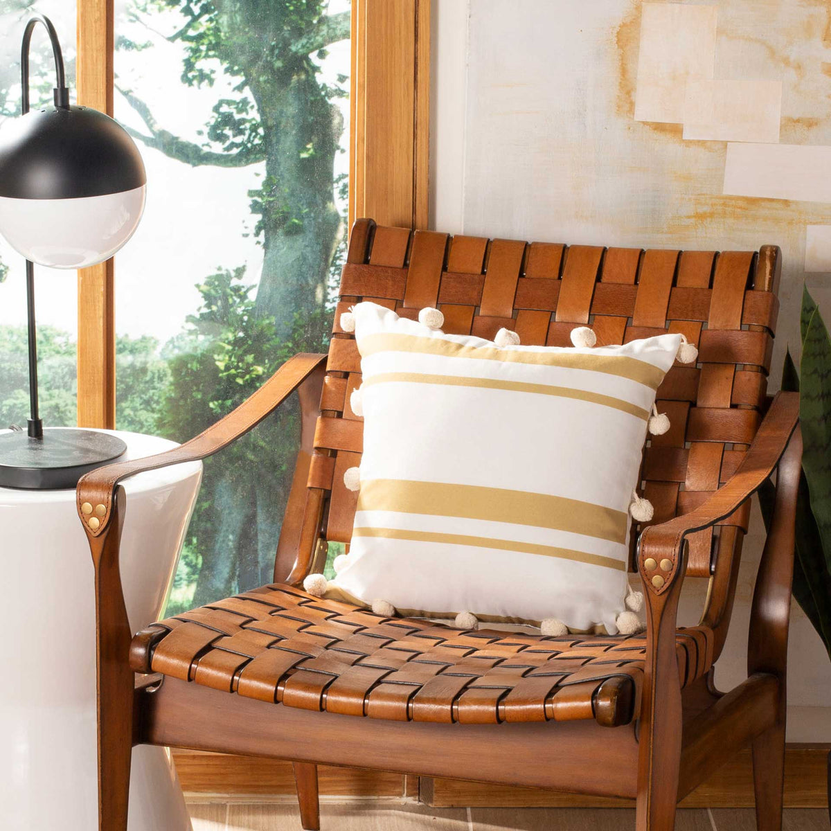 White and gold striped pillow with playful pom-pom trim