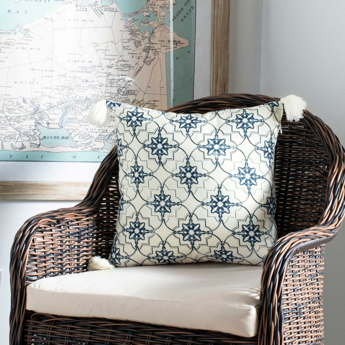 Tasseled corners add playful texture to a white pillow with an intricate blue floral pattern