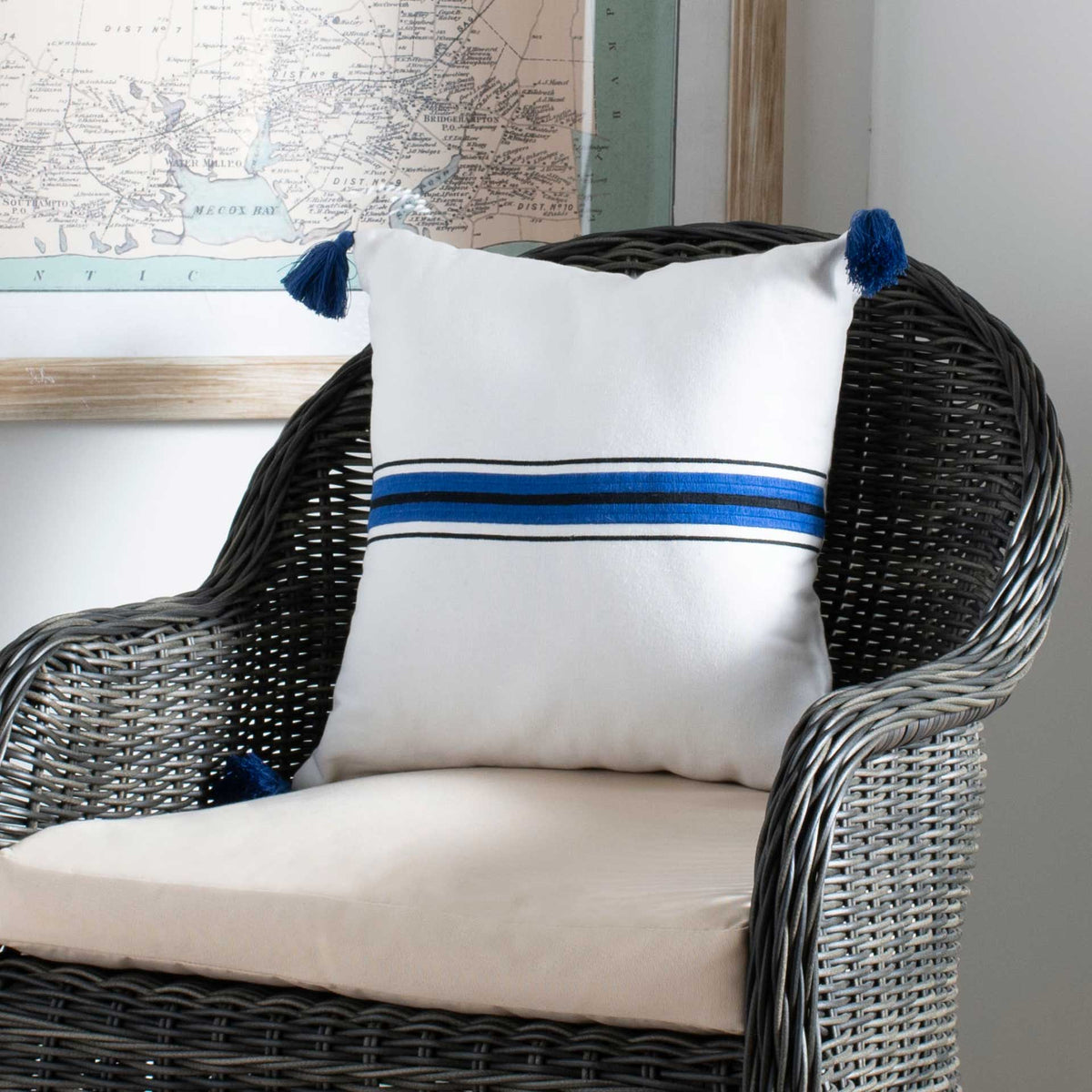 Navy and blue stripes cross a white pillow, bringing crisp contrast to a woven chair