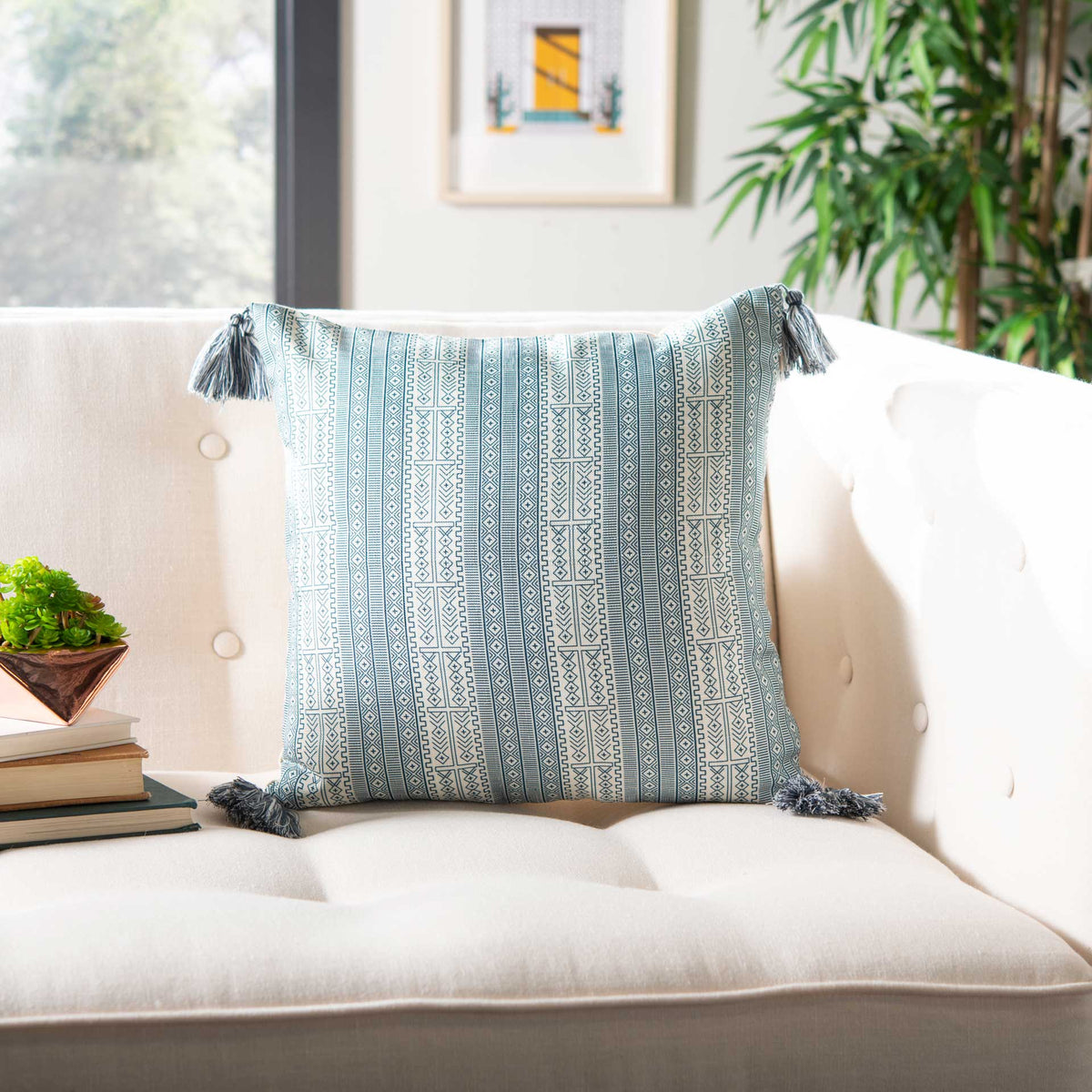 Four tasseled corners frame a crisp blue geometric pattern on this white accent pillow.