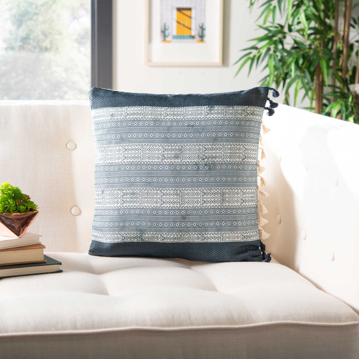 A navy-trimmed pillow with repeating blue geometric bands adds crisp pattern to a light sofa.