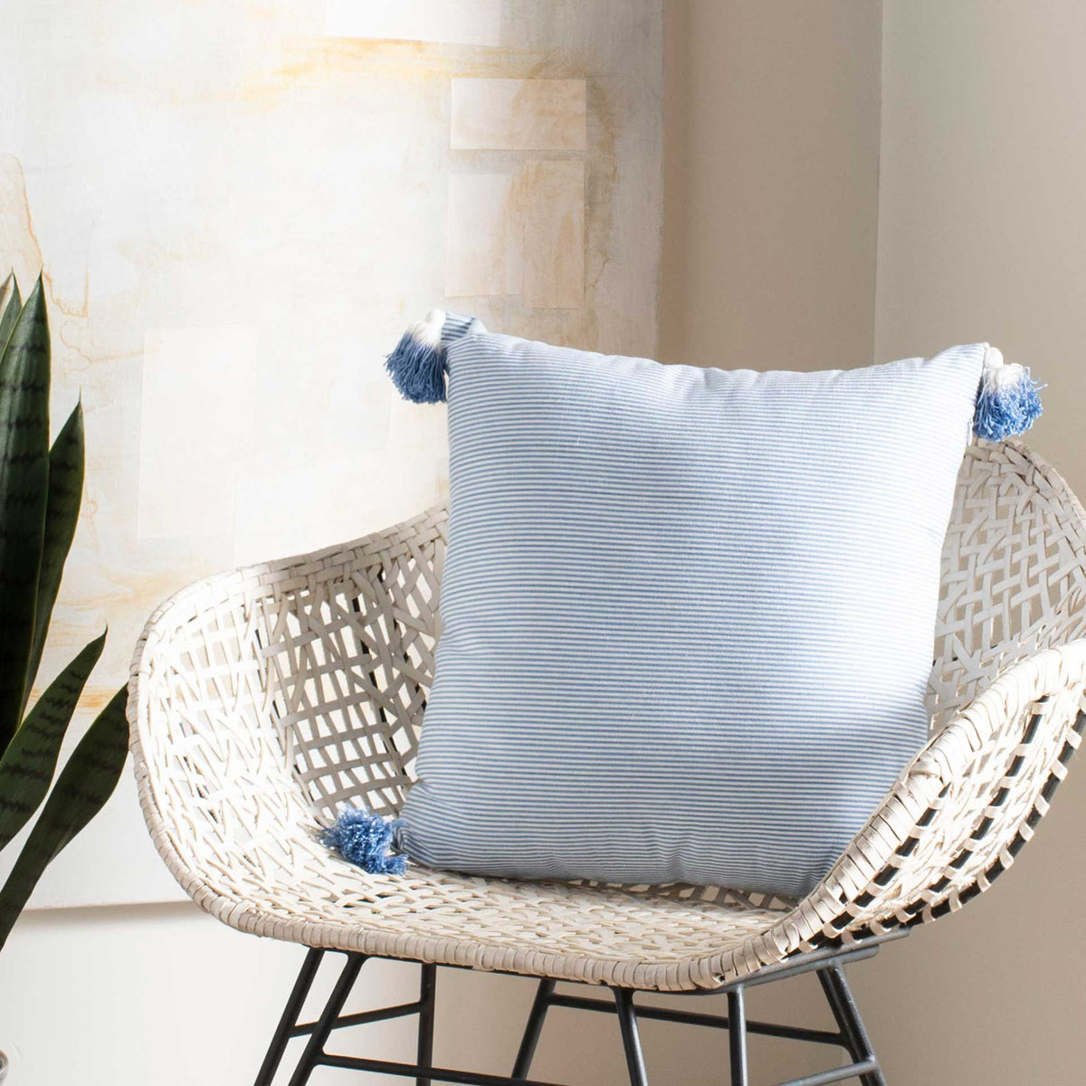 A blue-striped pillow with tasseled corners brings an airy accent to a woven chair.