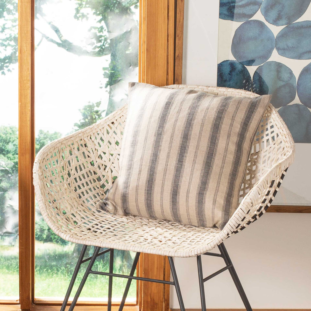 Blue-striped linen pillow brings a soft, casual accent to a woven chair