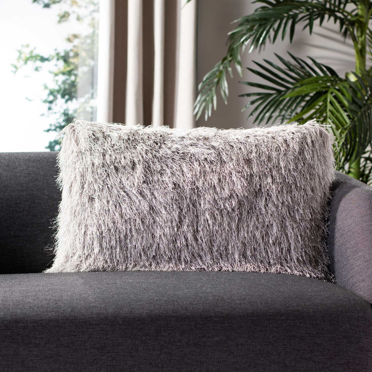 A silver shag lumbar pillow adds plush texture to a charcoal sofa.