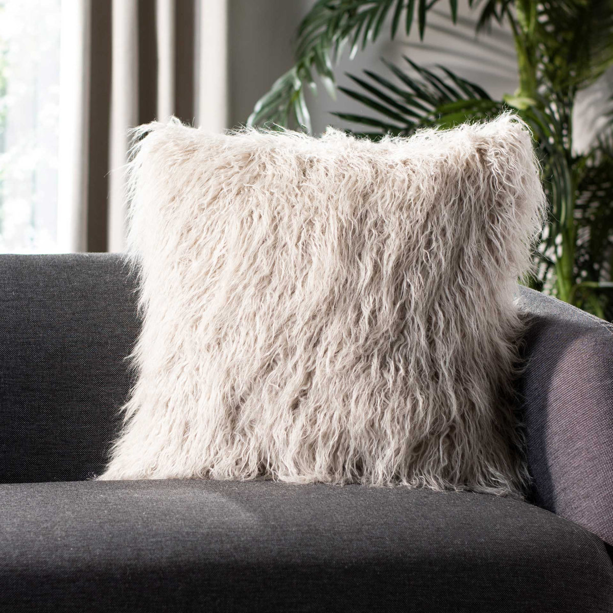 Wispy gray faux fur brings a cozy accent to a charcoal sofa.