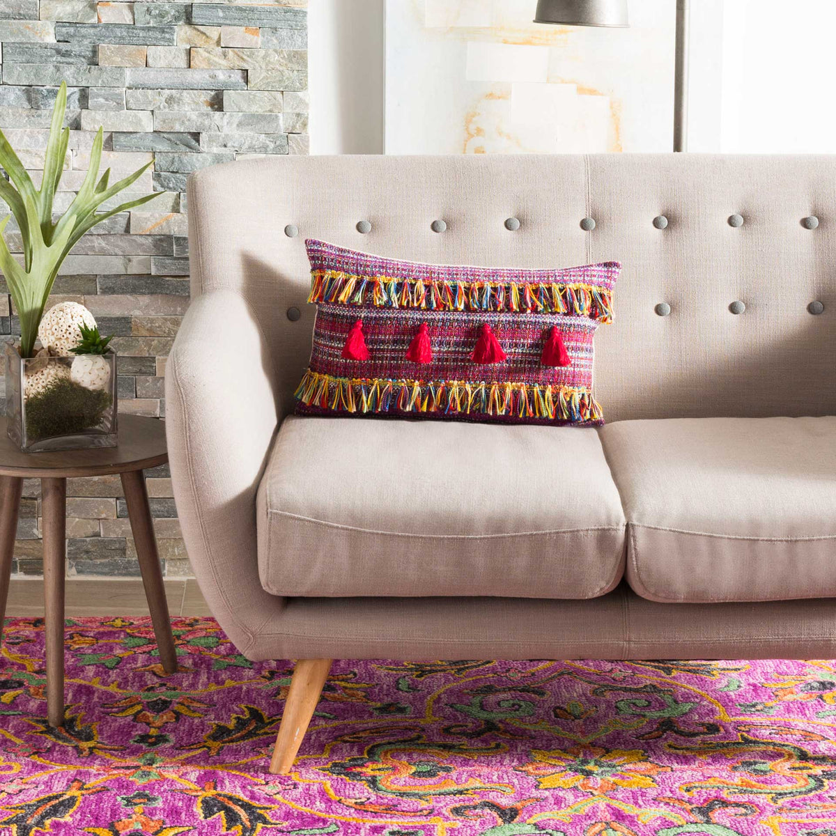 Bright woven pillow with red tassels and multicolor fringe adds a lively accent to a neutral sofa
