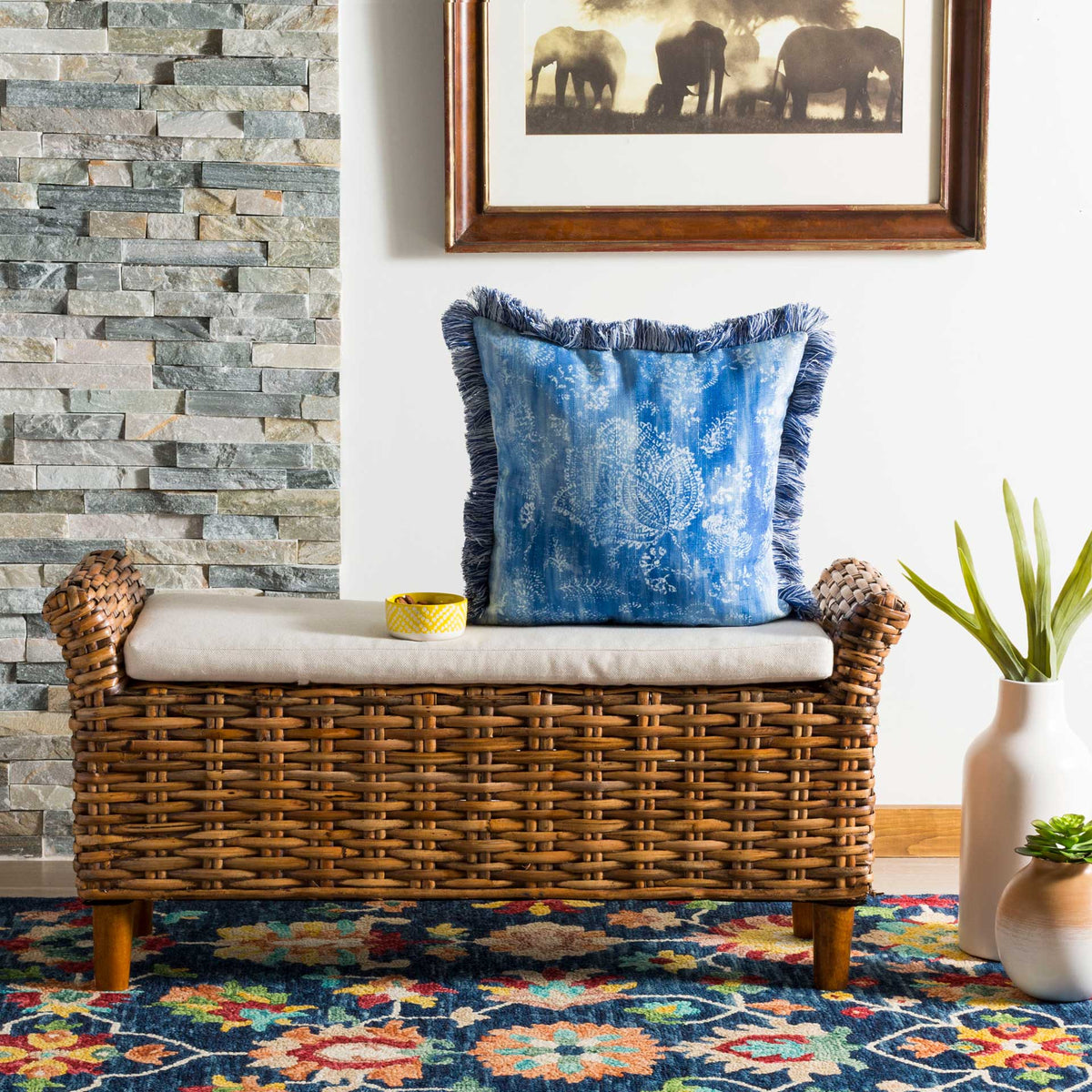 Blue fringed pillow adds a soft botanical pattern to a woven bench