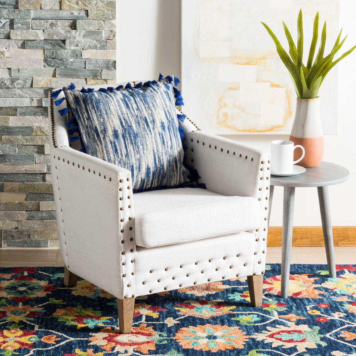 Navy and cream textured pillow with tassels adds a bold accent to a pale upholstered chair
